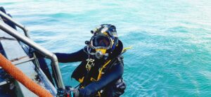 Commercial diver in a dive helmet beside the TSS dive boat