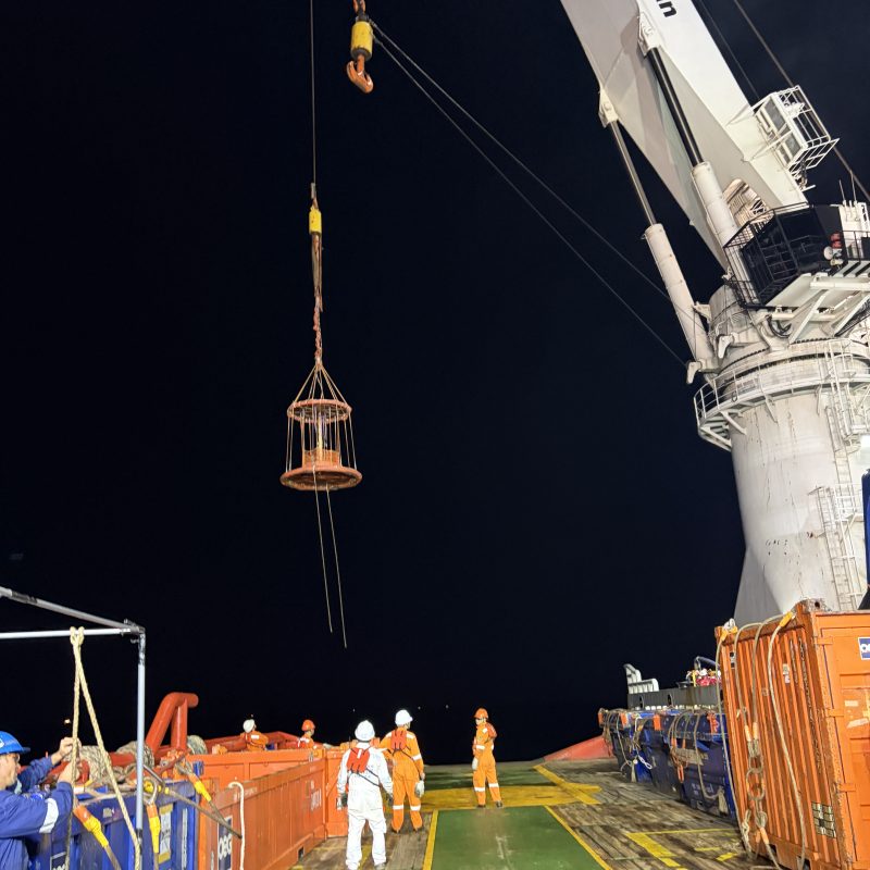 Dive basket lowered by crane during night operations offshore