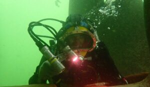 TSS diver inspecting a ship hull with a camera and light